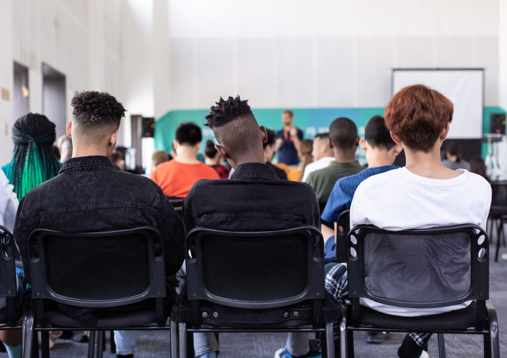 View fom rth eback of a lecture room, rows of chairs with students seated